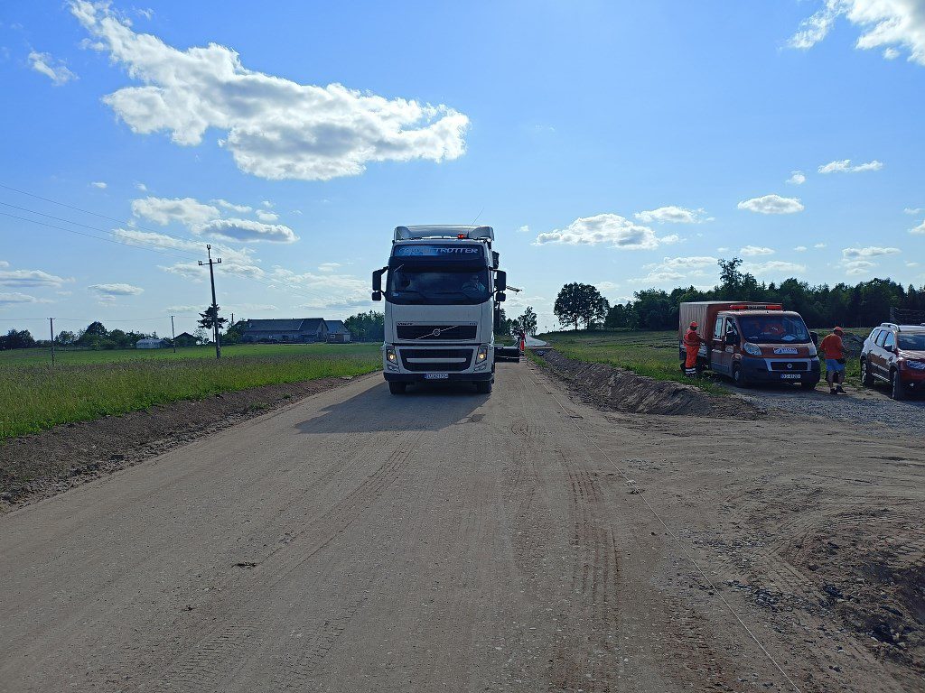 Biała ciężarówka Volvo jadąca po budowanej drodze gruntowej w wiejskiej okolicy