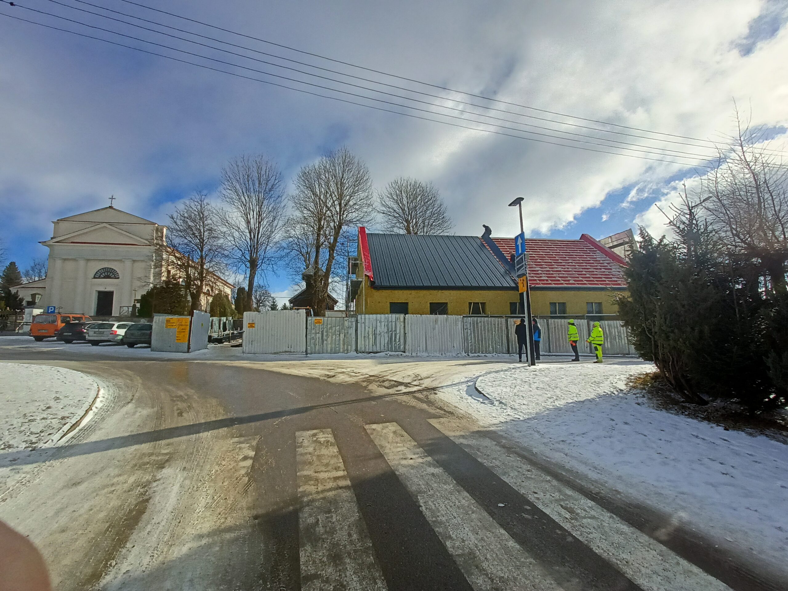 Prace dekarskie na budynku w sąsiedztwie kościoła w zimowej scenerii