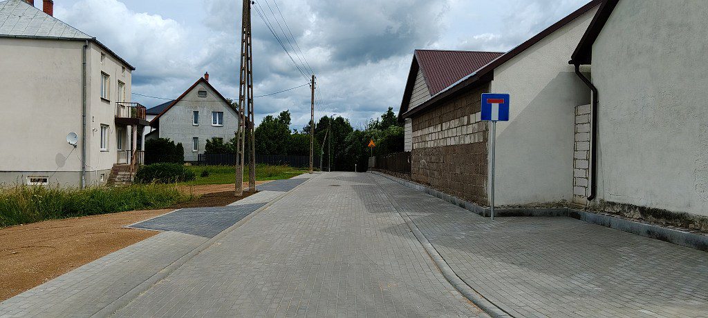Nowo wybrukowana ulica między domami ze znakiem droga bez wylotu