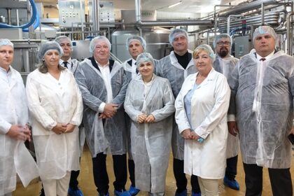 Grupa osób w odzieży ochronnej na tle maszyn w zakładzie produkcyjnym