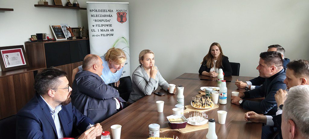 Spotkanie w Spółdzielni Mleczarskiej Rospuda w Filipowie; uczestnicy siedzą przy stole z produktami mlecznymi
