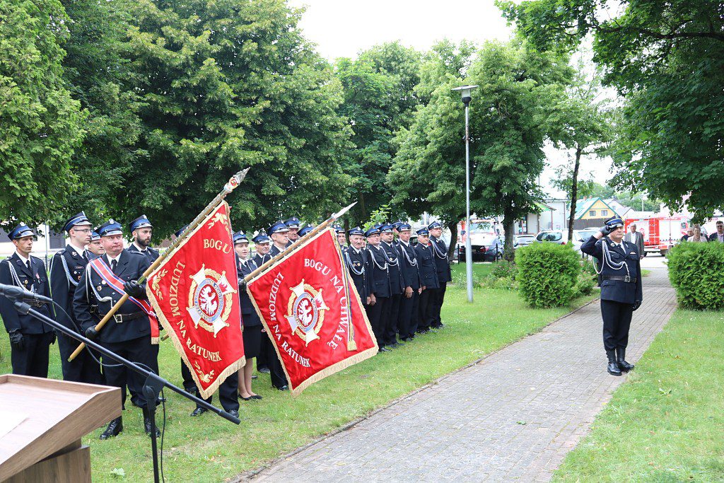 Strażacy w mundurach galowych ze sztandarami z hasłem Bogu na chwałę, ludziom na ratunek podczas uroczystości