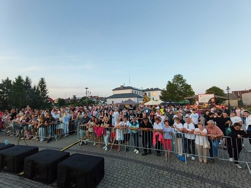 Tłum ludzi za barierkami ochronnymi podczas imprezy plenerowej na miejskim placu