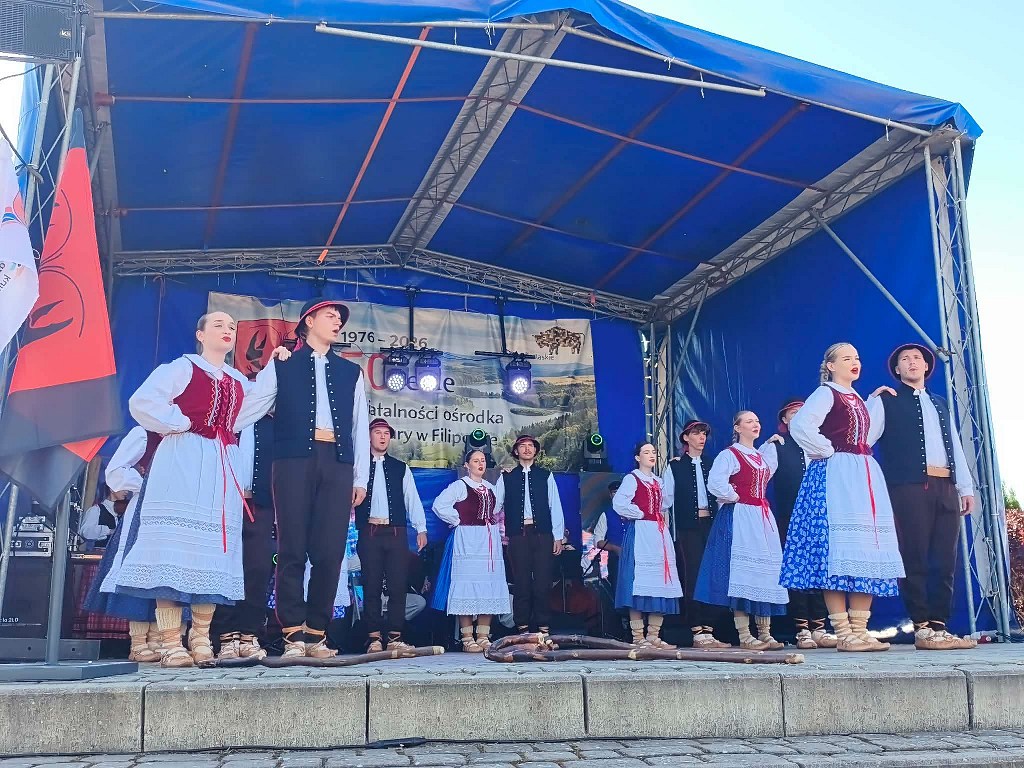 Zespół ludowy w tradycyjnych strojach występuje na scenie plenerowej podczas jubileuszu w Filipowie