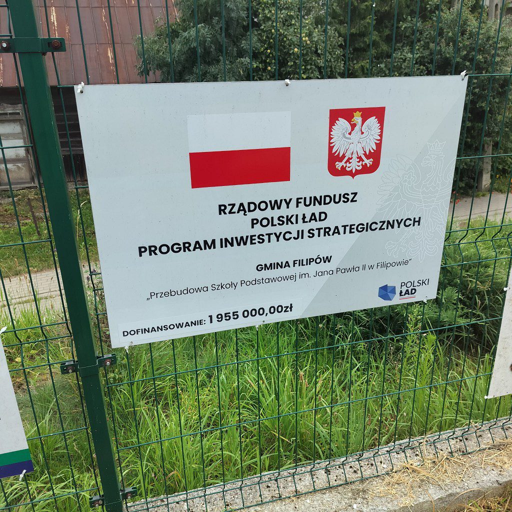 Tablica informacyjna o dofinansowaniu 1 955 000 zł z Polskiego Ładu na przebudowę szkoły podstawowej w Filipowie