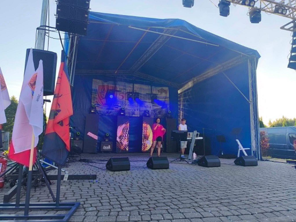 Kobieta śpiewająca na zadaszonej scenie plenerowej podczas koncertu