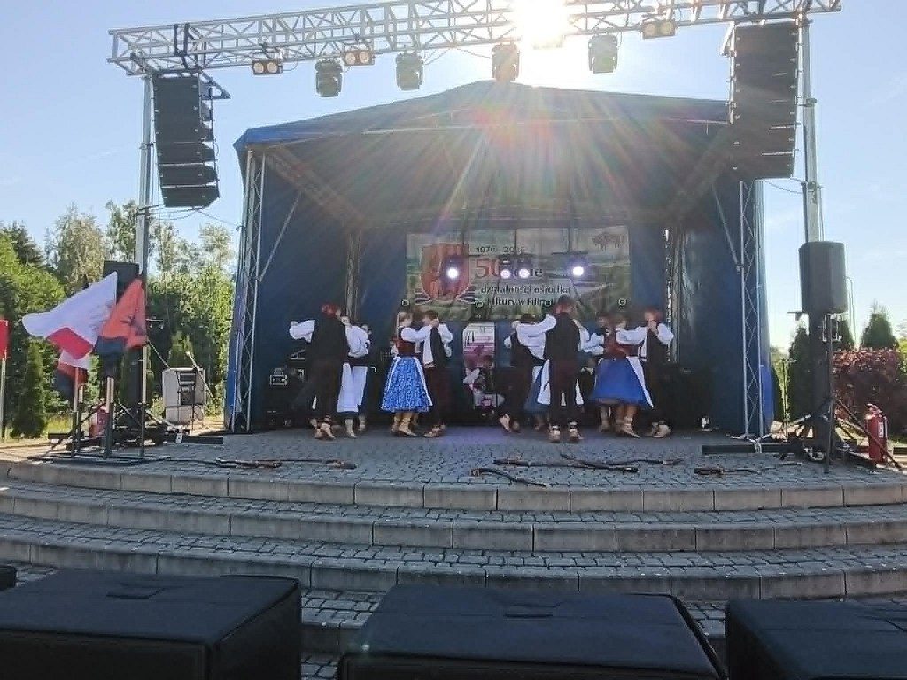 Zespół ludowy tańczący na plenerowej scenie podczas jubileuszu ośrodka kultury w Filipowie