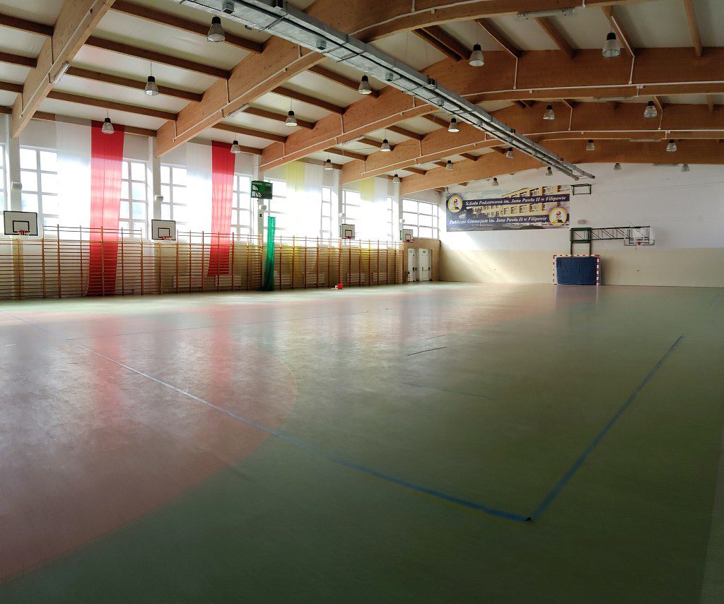 Wnętrze hali sportowej Szkoły Podstawowej w Filipowie z drabinkami, koszami do koszykówki i bramką