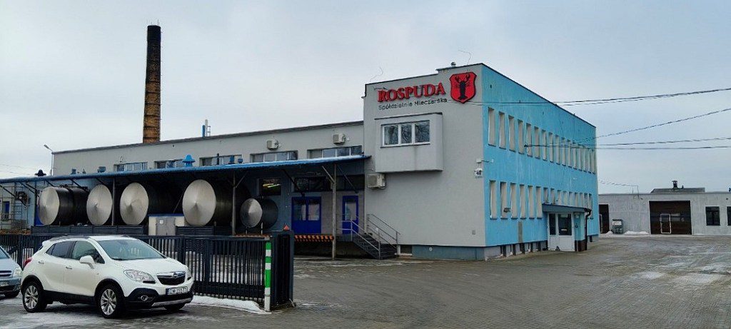 Budynek Spółdzielni Mleczarskiej Rospuda z logo, silosami i wysokim kominem