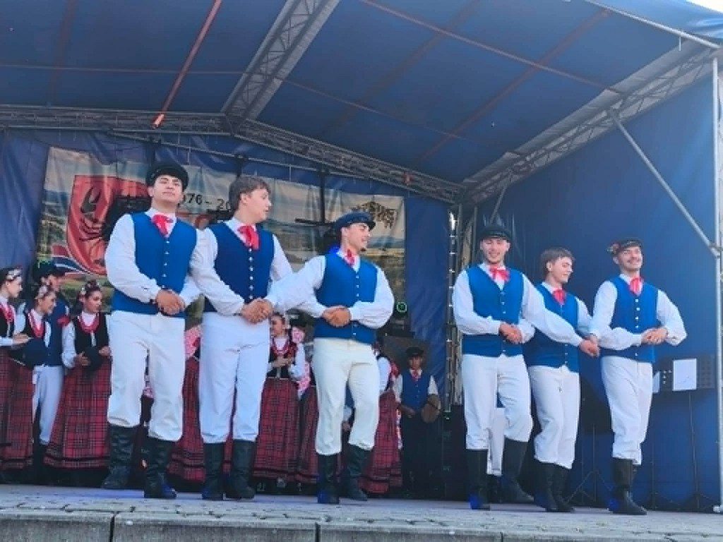 Mężczyźni w tradycyjnych strojach ludowych tańczący na scenie