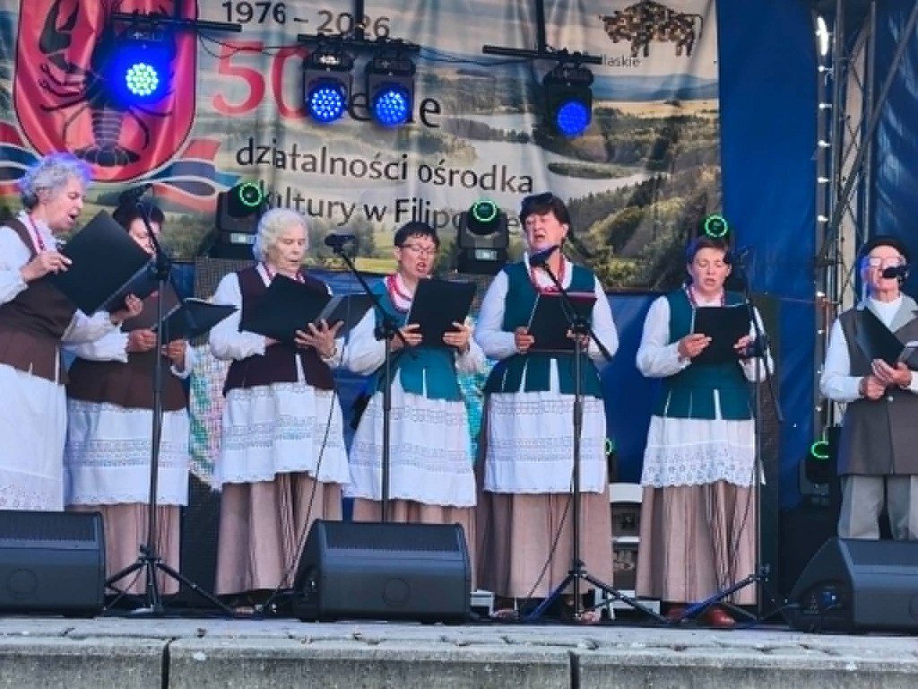 Zespół ludowy w tradycyjnych strojach śpiewa na scenie podczas obchodów 50-lecia ośrodka kultury w Filipowie