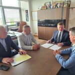 Czterej mężczyźni w garniturach siedzący przy stole w biurze i omawiający dokumenty