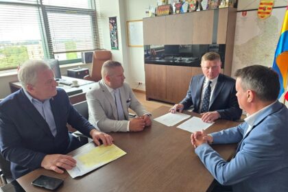 Czterej mężczyźni w garniturach siedzący przy stole w biurze i omawiający dokumenty