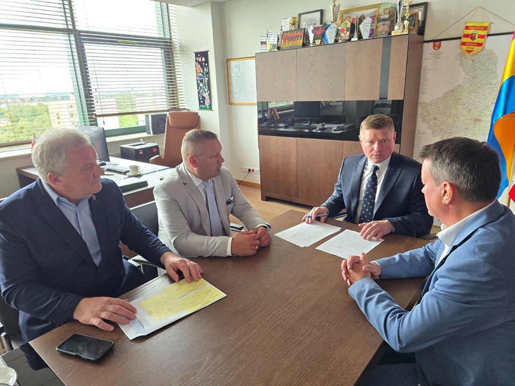 Czterej mężczyźni w garniturach siedzący przy stole w biurze i omawiający dokumenty