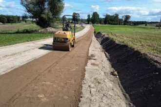 Żółty walec drogowy utwardzający nawierzchnię powstającej drogi