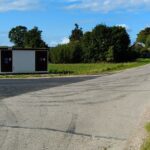 Asfaltowa droga wiejska ze stacją transformatorową po lewej i drogowskazem z napisem Zusno 3 po prawej