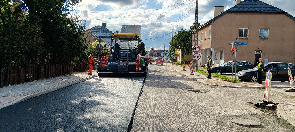 Rozściełacz asfaltu i robotnicy podczas układania nowej nawierzchni na ulicy osiedlowej