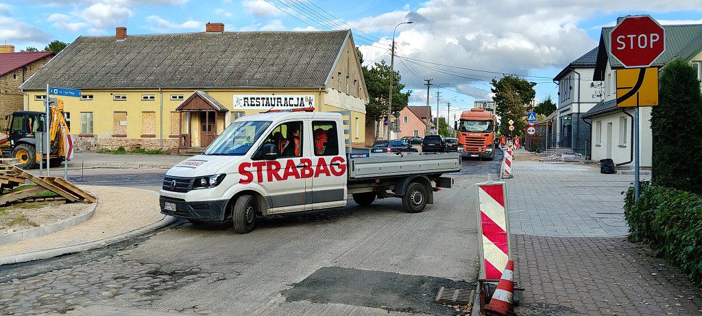 Biały samochód dostawczy firmy Strabag na przebudowywanej ulicy w trakcie prac drogowych
